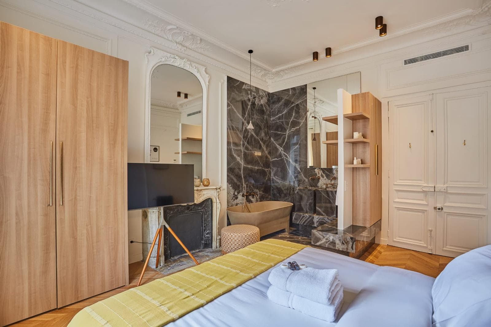 Chambre ouverte sur une salle de bain en marbre, moulures et miroir ancien conservés