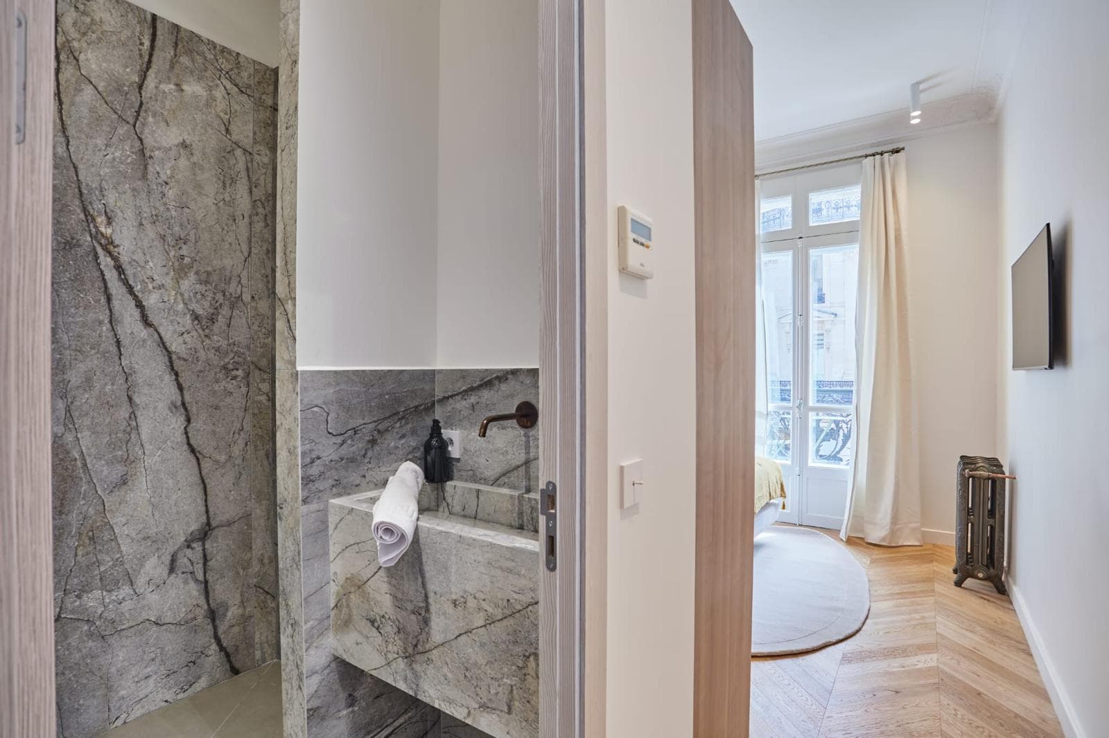 Salle d’eau en marbre gris avec niche et robinetterie encastrée noire