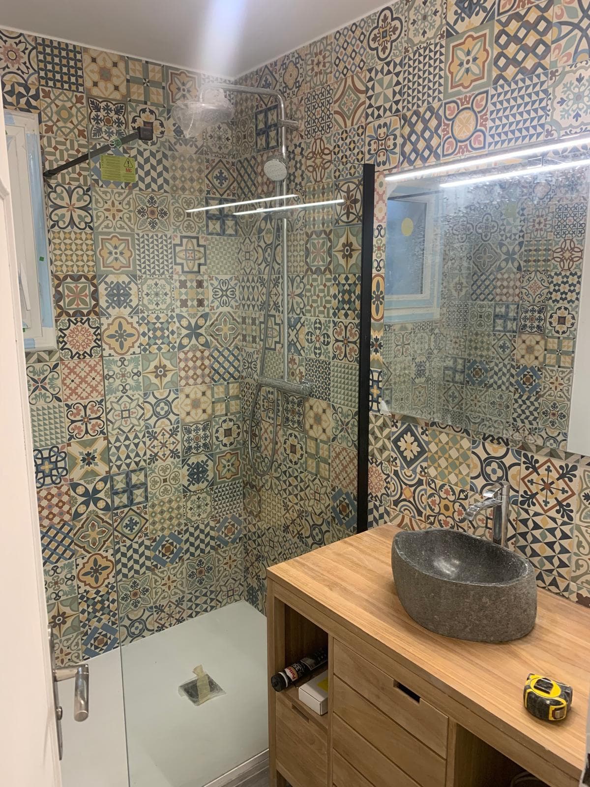 Douche en carreaux de ciment, vasque en pierre posée sur un meuble en bois